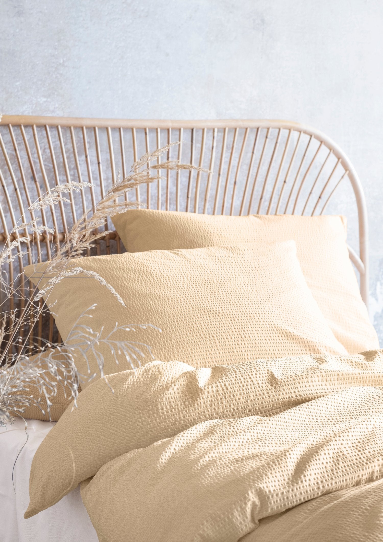 Auf einem Bett liegen mehrere Kopfkissen und eine Bettdecke bezogen mit Soft Seersucker Bettwaesche aus 100 Prozent Baumwolle in der Farbe Gelb. Modell Easy Yellow.