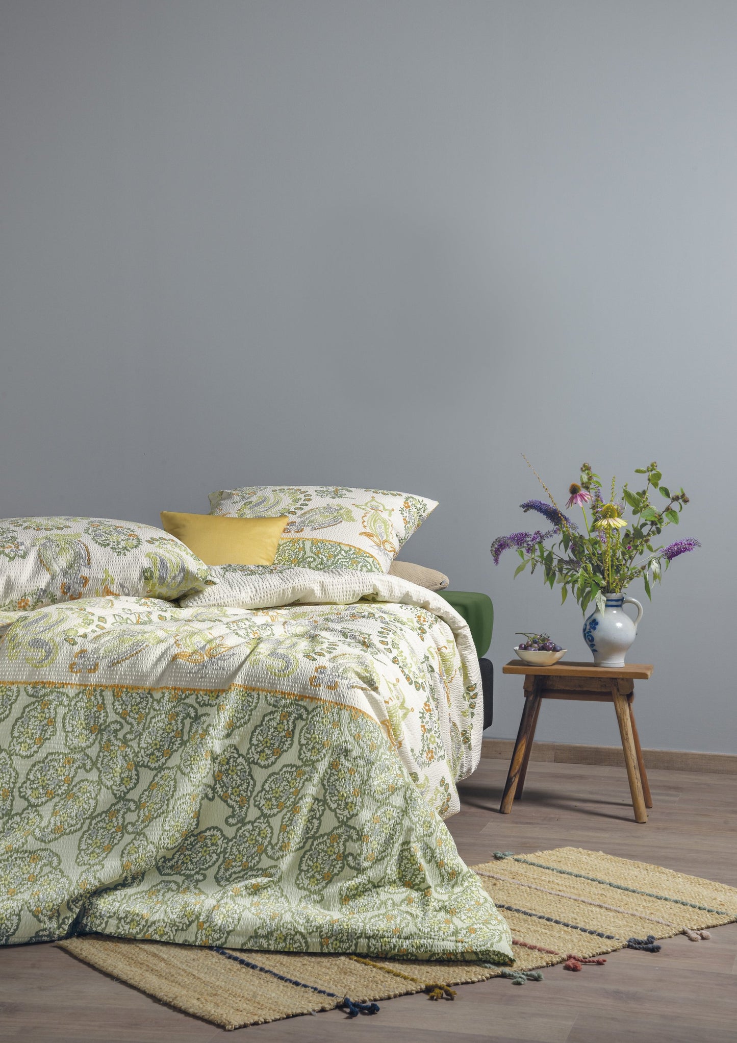 Auf einem Bett liegen mehrere Kopfkissen und eine Bettdecke bezogen mit Soft Seersucker Bettwaesche aus 100 Prozent Baumwolle mit Muster aus Ornamenten in der Farbe Gruen. Modell Shadow Green.
