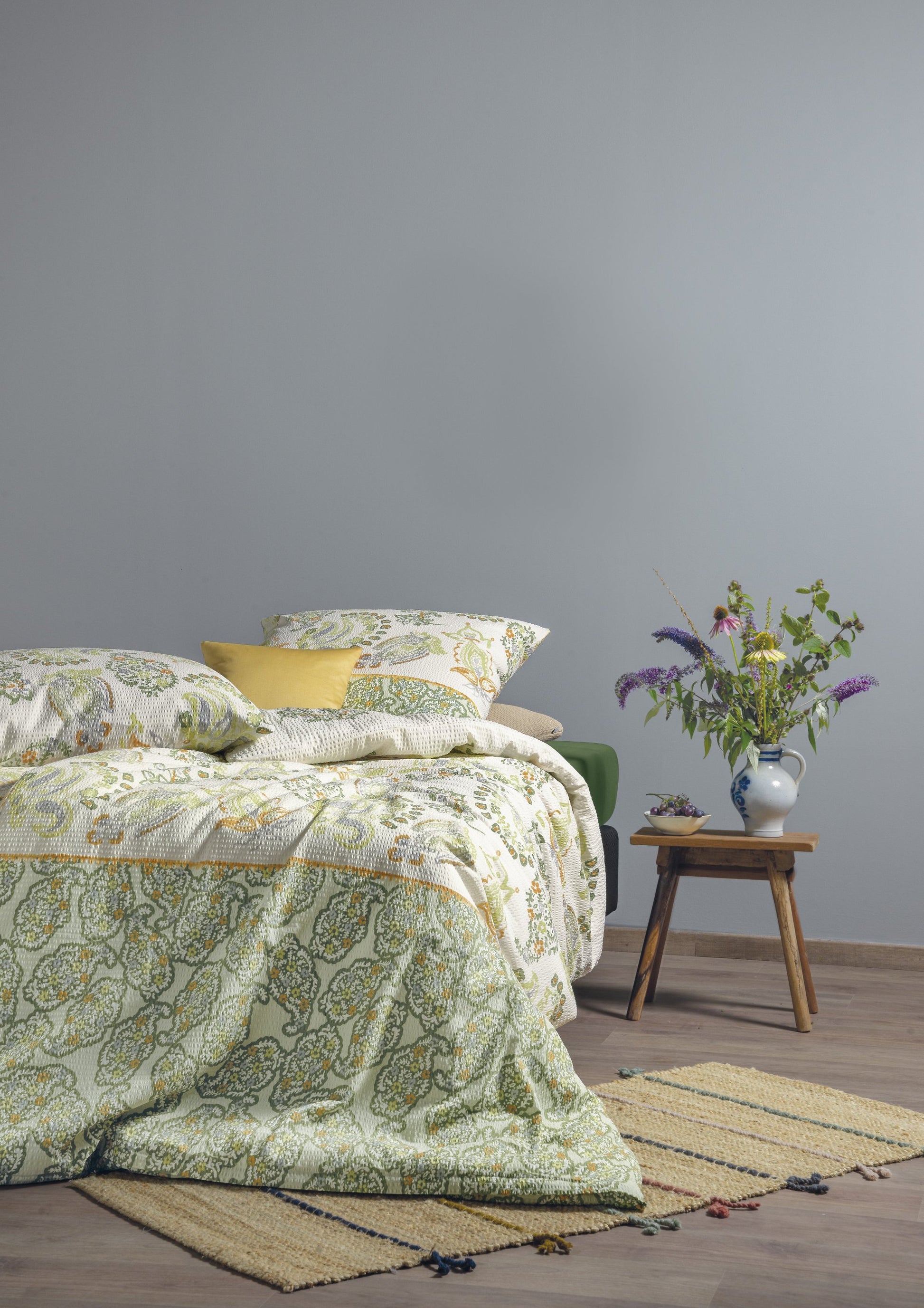 Auf einem Bett liegen mehrere Kopfkissen und eine Bettdecke bezogen mit Soft Seersucker Bettwaesche aus 100 Prozent Baumwolle mit Muster aus Ornamenten in der Farbe Gruen. Modell Shadow Green.