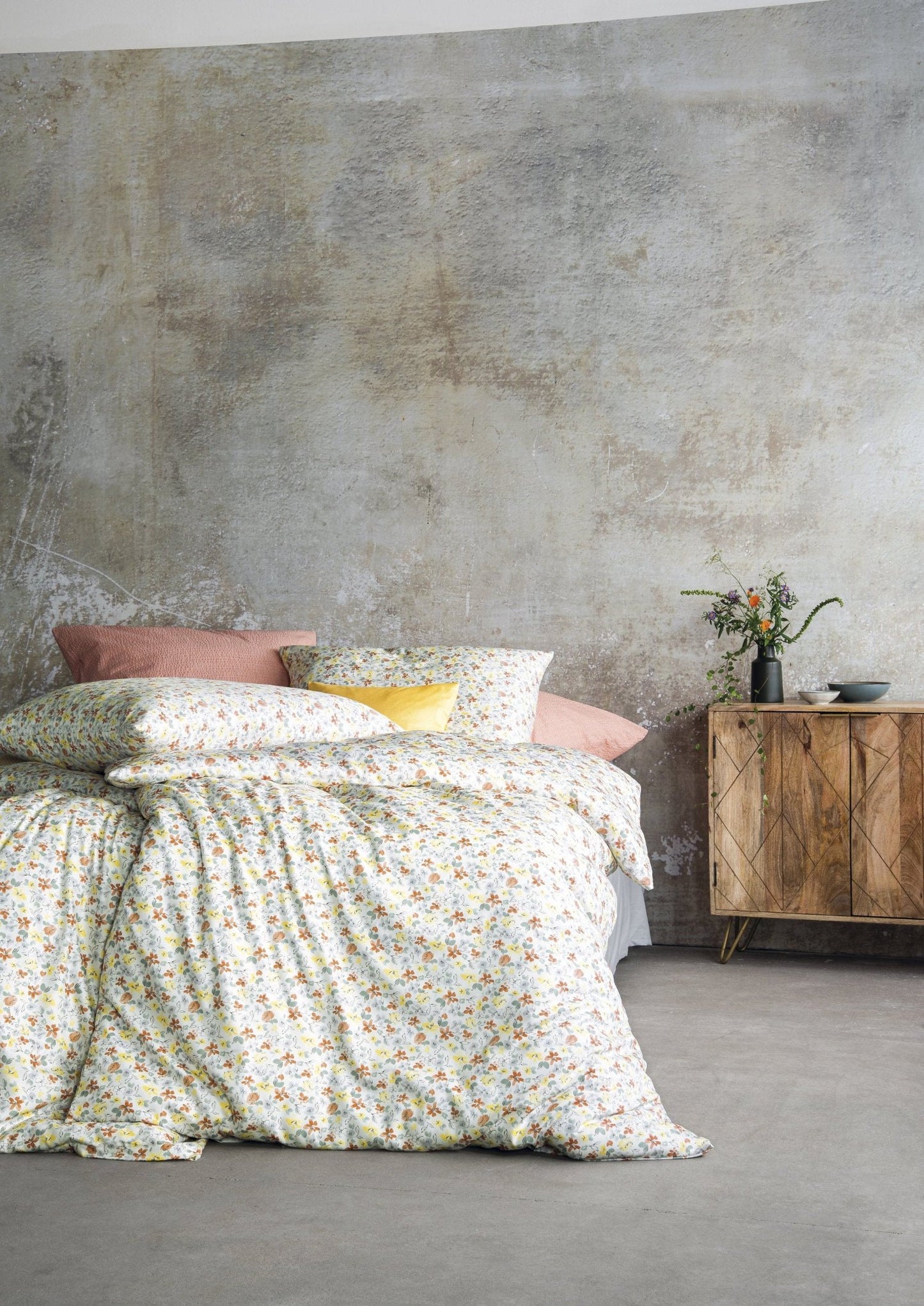 Auf einem Bett liegen mehrere Kopfkissen und eine Bettdecke bezogen mit Soft Seersucker Bettwaesche aus 100 Prozent Baumwolle mit Muster aus Blumen in der Farbe Gelb. Modell Shadow Multi.