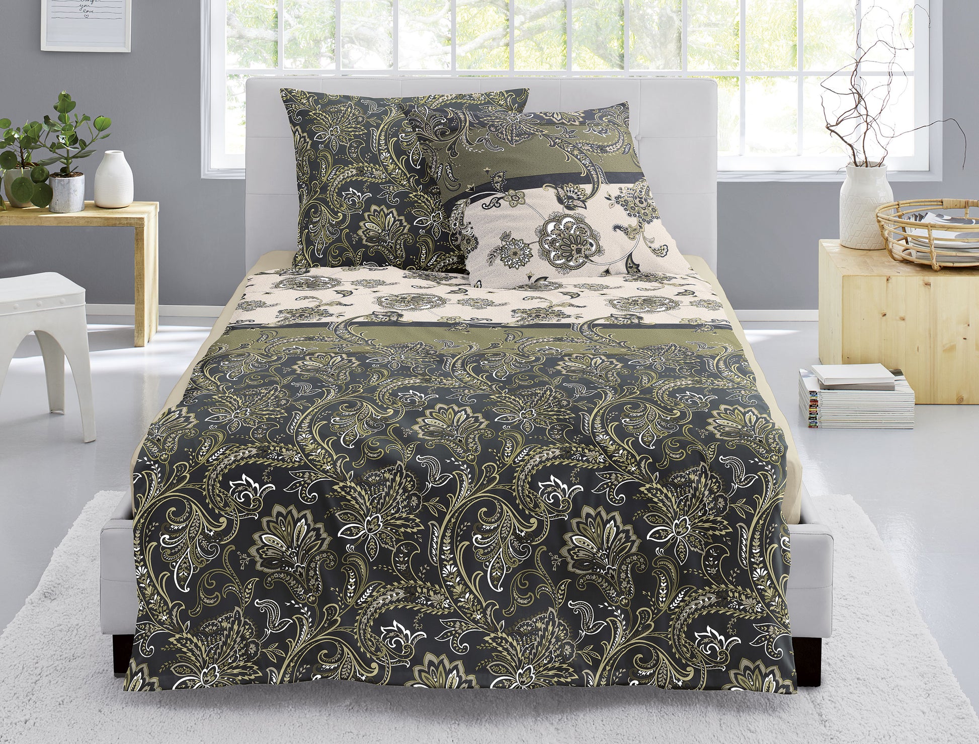 Auf einem Bett liegen mehrere Kopfkissen und eine Bettdecke bezogen mit Edel-Feinbiber Bettwaesche aus 100 Prozent Baumwolle mit Muster aus Ornamenten in der Farbe Gruen. Modell Luzara.