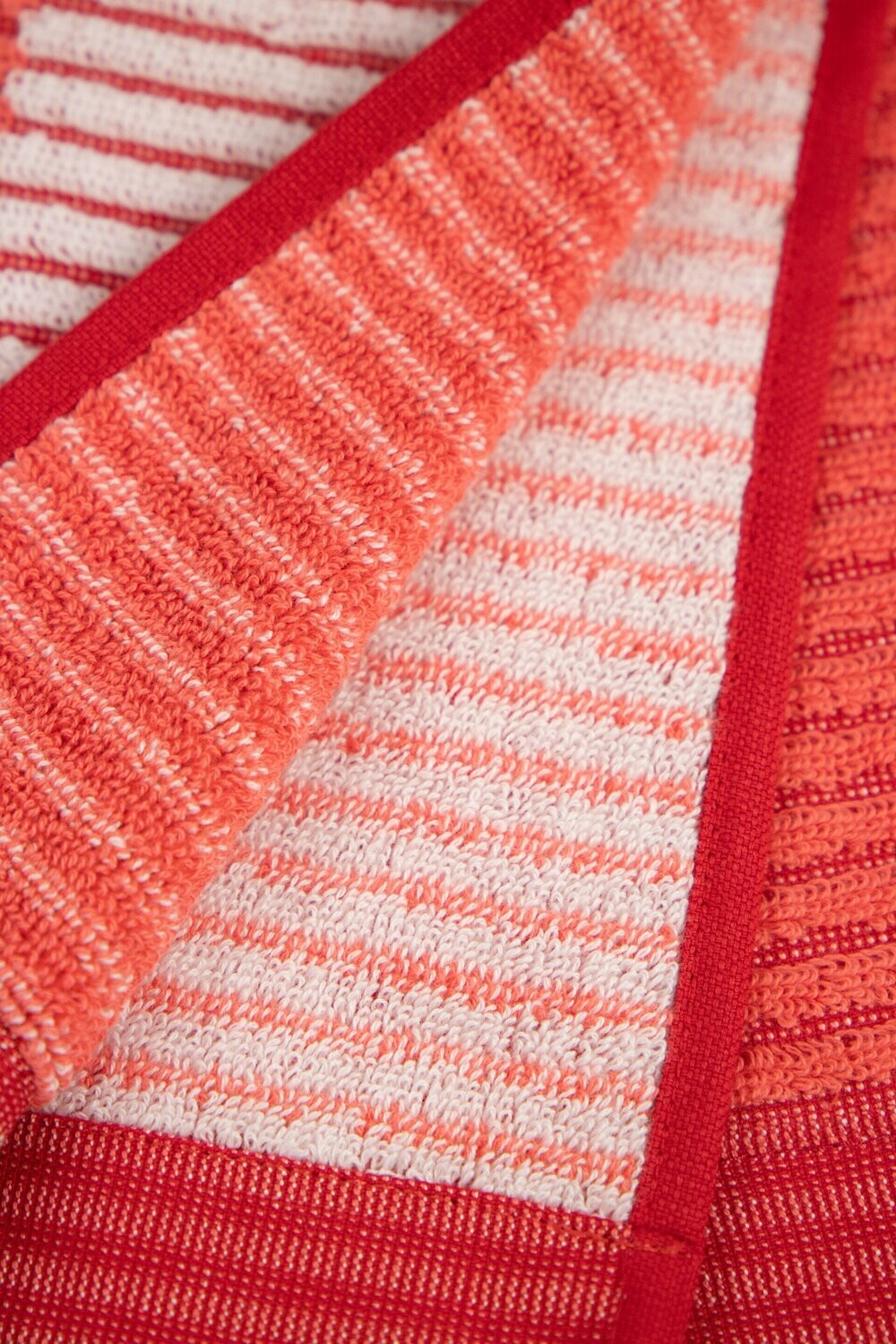 Eine Detailaufnahme von mehreren Handtuechern die aufeinander liegen in der Farbe Rot. Die Struktur wird hervorgehoben. Modell Bloki Cayenne. 