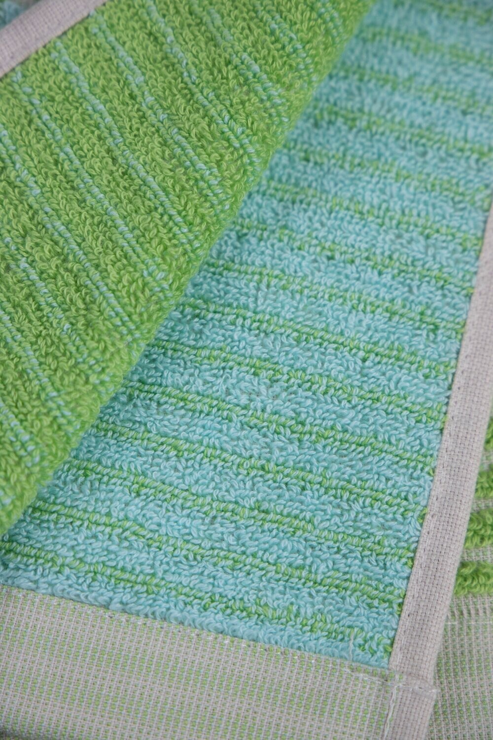 Eine Detailaufnahme von mehreren Handtuechern die aufeinander liegen in der Farbe Gruen. Die Struktur wird hervorgehoben. Modell Bloki Lime.