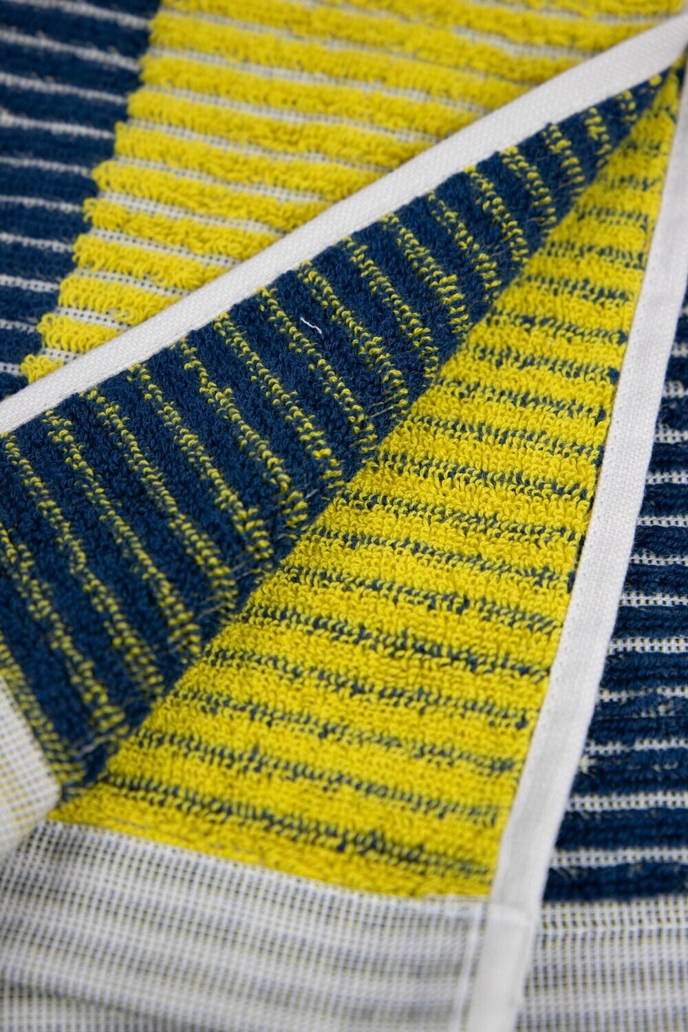 Eine Detailaufnahme von mehreren Handtuechern die aufeinander liegen in der Farbe Gelb. Die Struktur wird hervorgehoben. Modell Bloki Mustard.