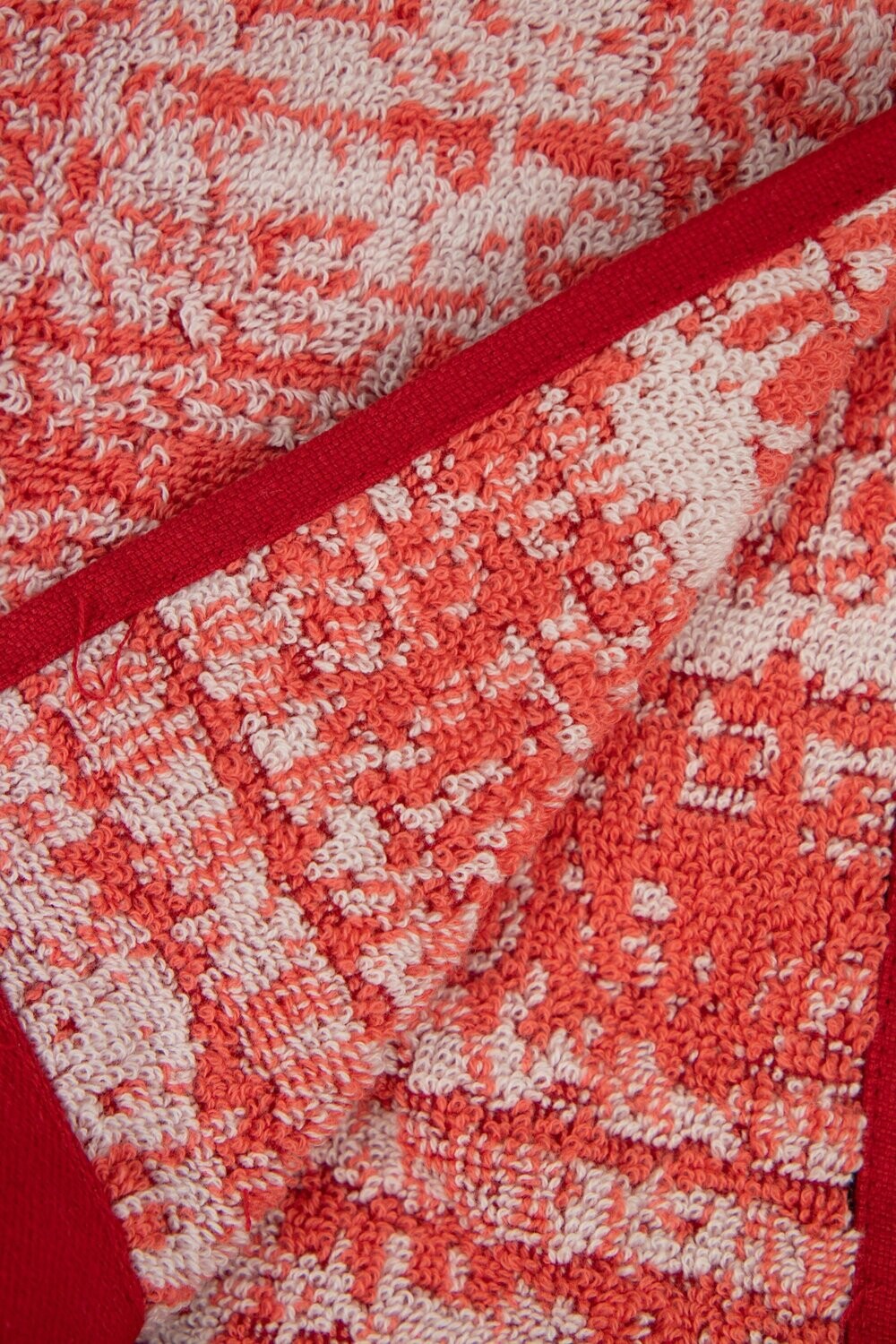 Eine Detailaufnahme von mehreren Handtuechern die aufeinander liegen in der Farbe Rot. Die Struktur wird hervorgehoben. Modell Mivu Cayenne.
