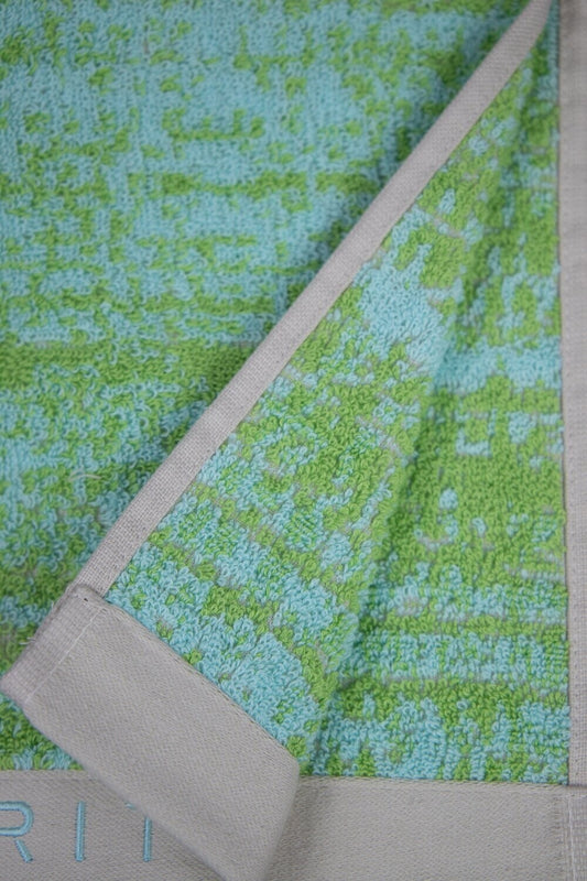 Eine Detailaufnahme von mehreren Handtuechern die aufeinander liegen in der Farbe Gruen. Die Struktur wird hervorgehoben. Modell Mivu Lime.