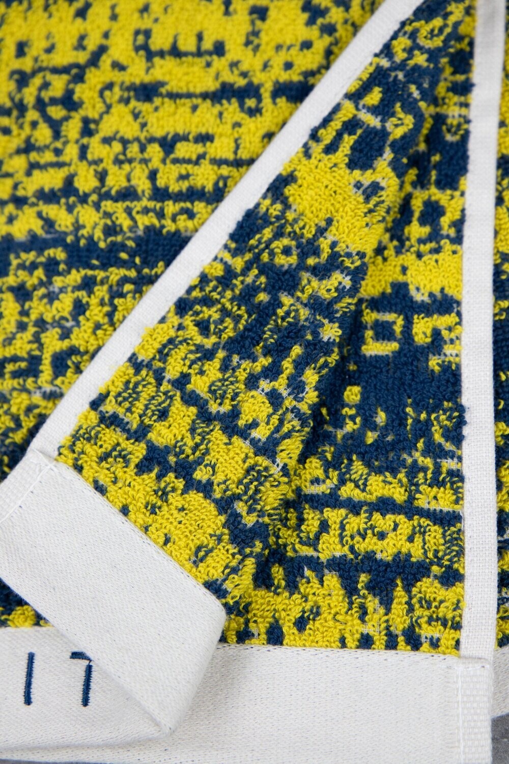 Eine Detailaufnahme von mehreren Handtuechern die aufeinander liegen in der Farbe Gelb. Die Struktur wird hervorgehoben. Modell Mivu Mustard.