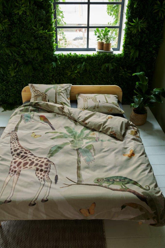 In einem Kinderzimmer steht ein Kinderbett mit einem Kopfkissen und einer Bettdecke bezogen mit kuscheliger Covers & Co Bettwaesche aus 100 Prozent Baumwolle mit Illustrationen vom Dschungel in der Farbe Beige. Modell Banana.