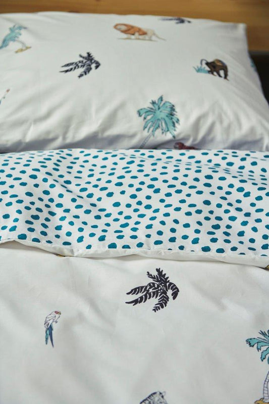 In einem Kinderzimmer steht ein Bett mit einem Kopfkissen und einer Bettdecke bezogen mit kuscheliger Covers & Co Bettwaesche aus 100 Prozent Baumwolle mit Illustrationen von wilden Steppentieren in der Farbe Weiss. Modell Into The Wild.