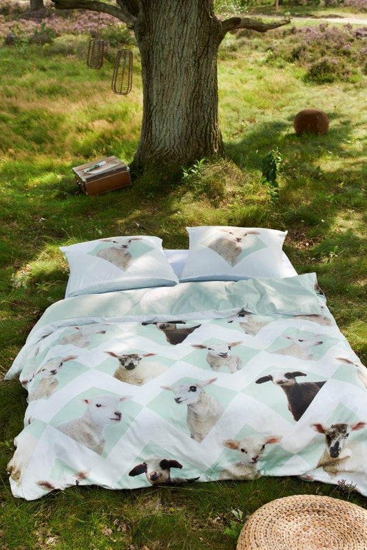 Ein Bett mit einem Kopfkissen und einer Bettdecke bezogen mit kuscheliger Covers & Co Bettwaesche aus 100 Prozent Baumwolle mit Illustrationen von Schafen in der Farbe Weiss. Modell Lamsy.
