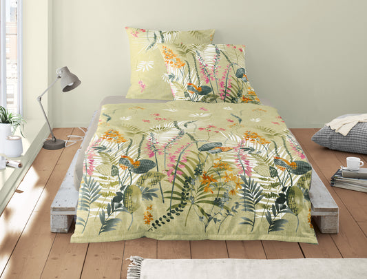 Auf einem Bett liegen mehrere Kopfkissen und eine Bettdecke bezogen mit Mako-Satin Bettwaesche aus 100 Prozent Baumwolle mit Muster aus Blaettern in der Farbe Gruen. Modell Fruehling Gruen.