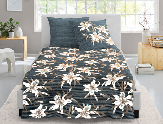 Auf einem Bett liegen mehrere Kopfkissen und eine Bettdecke bezogen mit Mako-Satin Bettwaesche aus 100 Prozent Baumwolle mit Muster aus Blumen in der Farbe Grau. Modell Lilly.