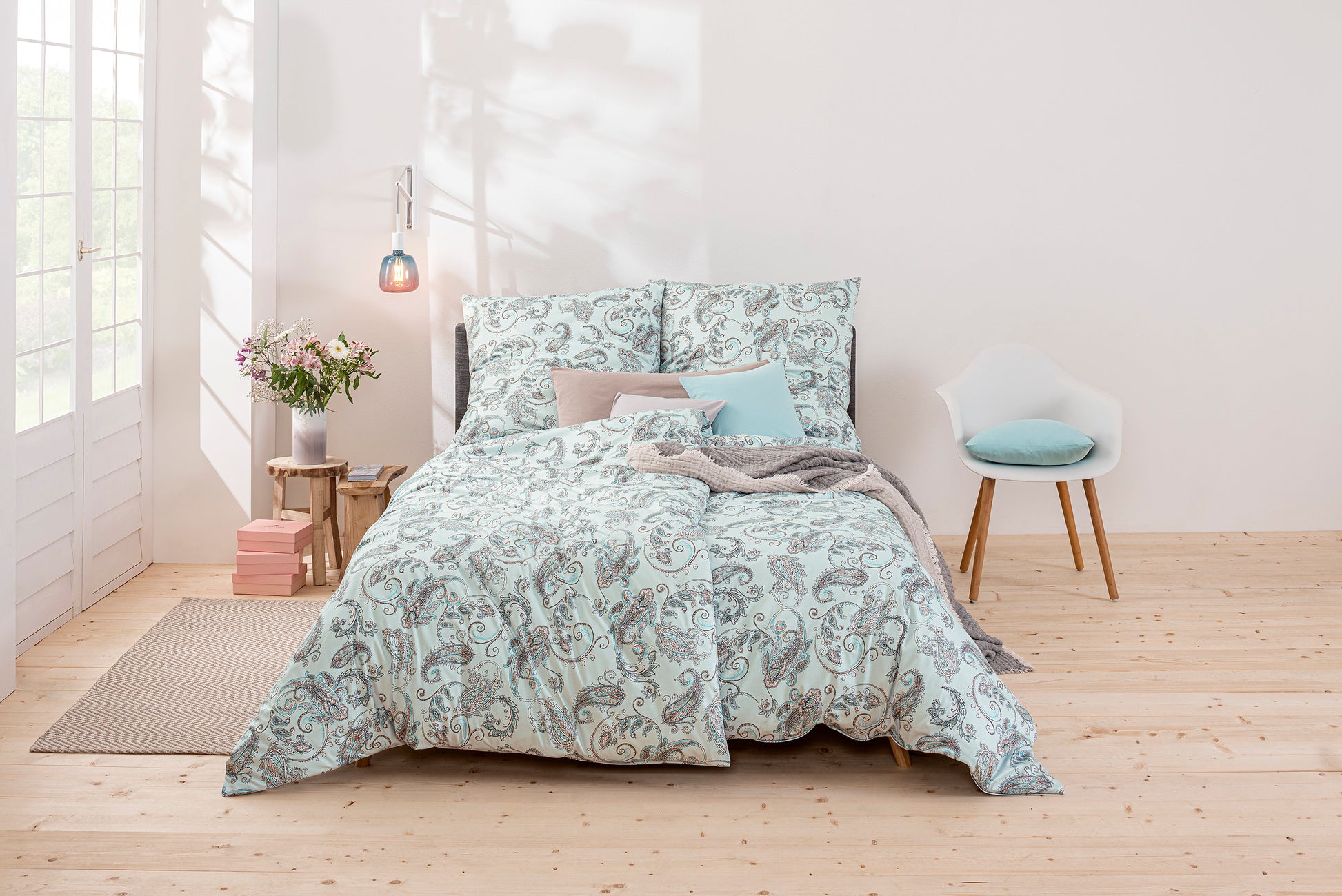 Ein Bettbezug-Set aus mehreren Kopfkissen und einer Bettdecke bezogen mit Mako-Interlock-Jersey Bettwaesche aus 100 Prozent Baumwolle mit Muster aus Ornamenten in der Farbe Blau. Modell Paisley hellblau.