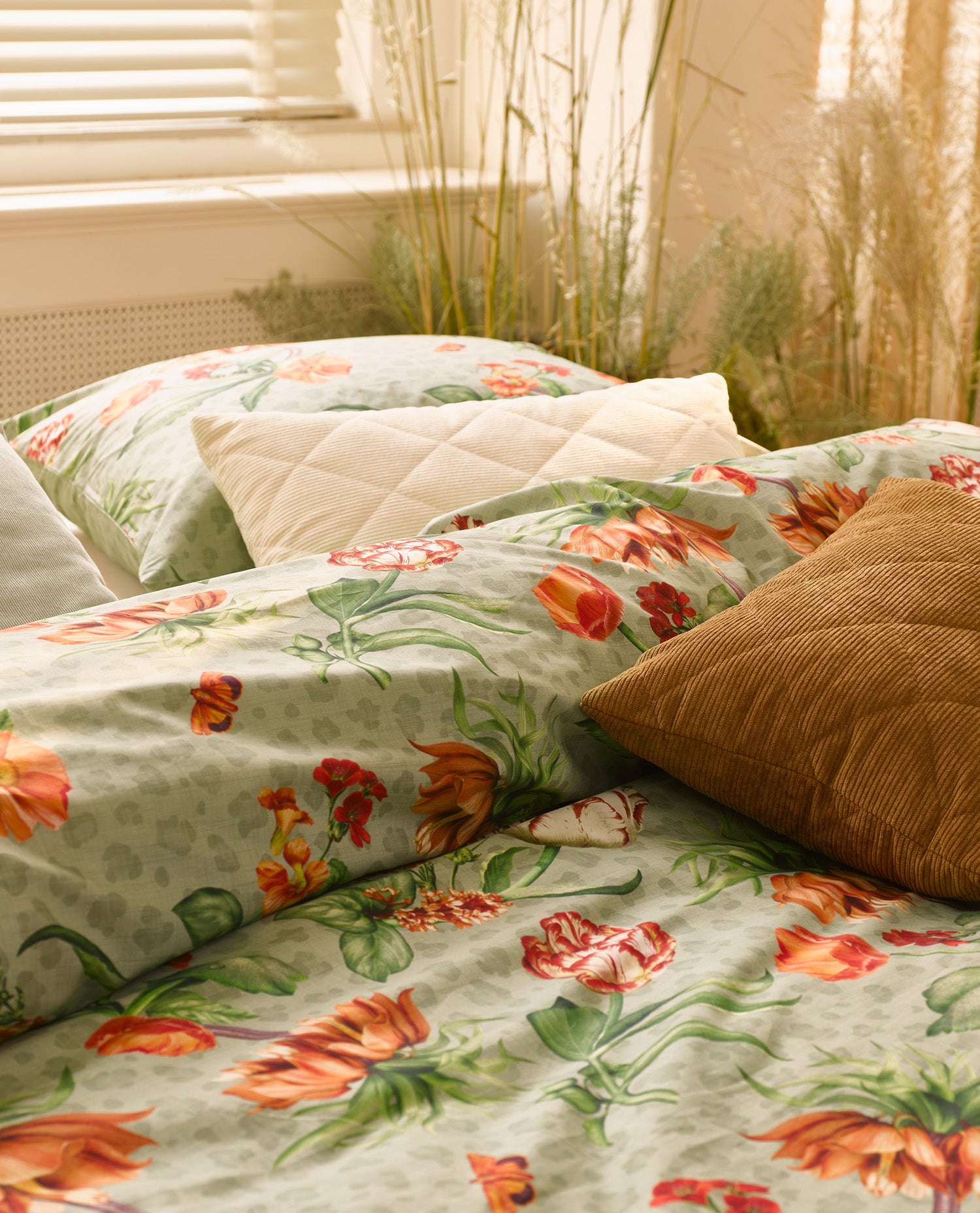 Ein Bettbezug-Set aus einem Kopfkissen und einer Bettdecke bezogen mit Perkal Bettwaesche aus 100 Prozent Baumwolle mit Muster aus Blumen in der Farbe Gruen. Modell Femm Green.