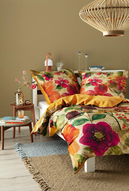 Mehrere Kopfkissen und eine Bettdecke bezogen mit kuscheliger Renforce Bettwaesche von beddinghouse mit einem floralem Muster in der Farbe Orange. Modell Summer.