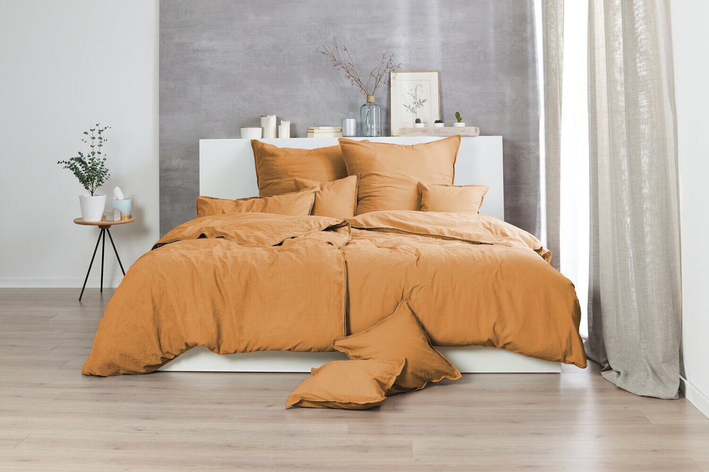 Auf einem Bett liegen mehrere Kopfkissen und eine Bettdecke bezogen mit Renforce Bettwaesche aus 100 Prozent Baumwolle in der Farbe Gelb. Modell Stone-Washed Curry 178.