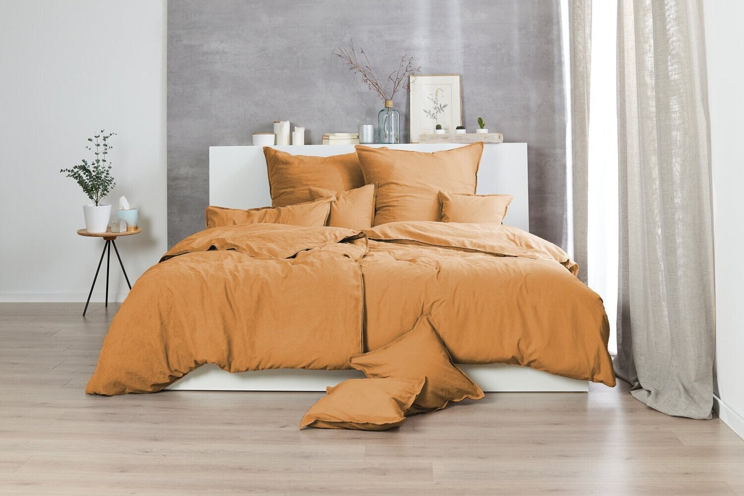 Auf einem Bett liegen mehrere Kopfkissen und eine Bettdecke bezogen mit Renforce Bettwaesche aus 100 Prozent Baumwolle in der Farbe Gelb. Modell Stone-Washed Curry 178.