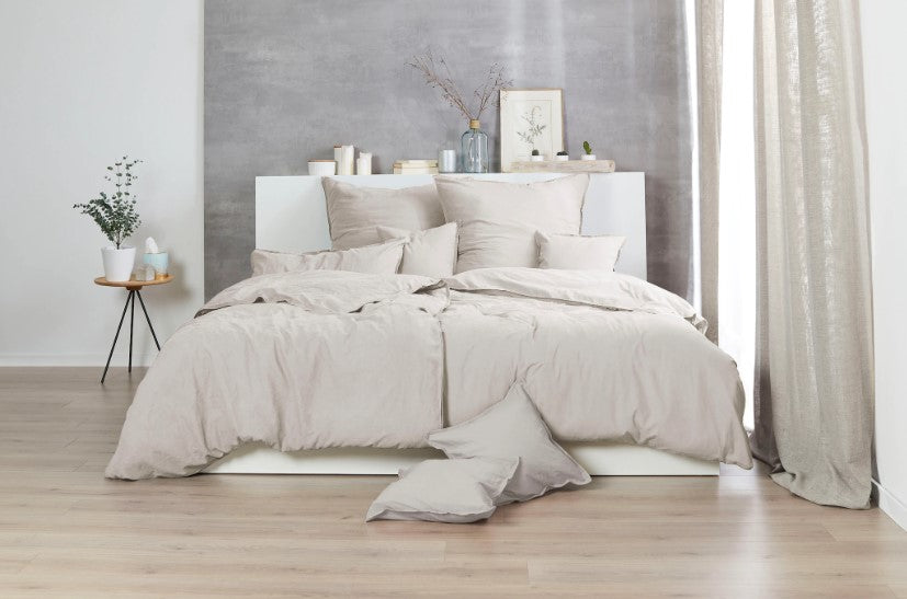 Auf einem Bett liegen mehrere Kopfkissen und eine Bettdecke bezogen mit Renforce Bettwaesche aus 100 Prozent Baumwolle in der Farbe Beige. Modell Stone-Washed Sand 719.