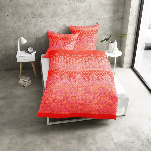 Mehrere Kopfkissen und eine Bettdecke bezogen mit seidig-weicher Satin Bettwaesche von Casatex mit einem Muster in der Farbe Orange. Modell Ajala Orange.