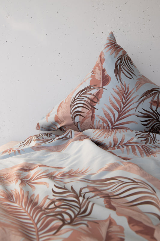 Ein Kopfkissen und eine Bettdecke bezogen mit seidig-weicher Satin Bettwaesche von Casatex mit einem Muster in der Farbe Tuerkis. Modell Indi Tuerkis/Braun.