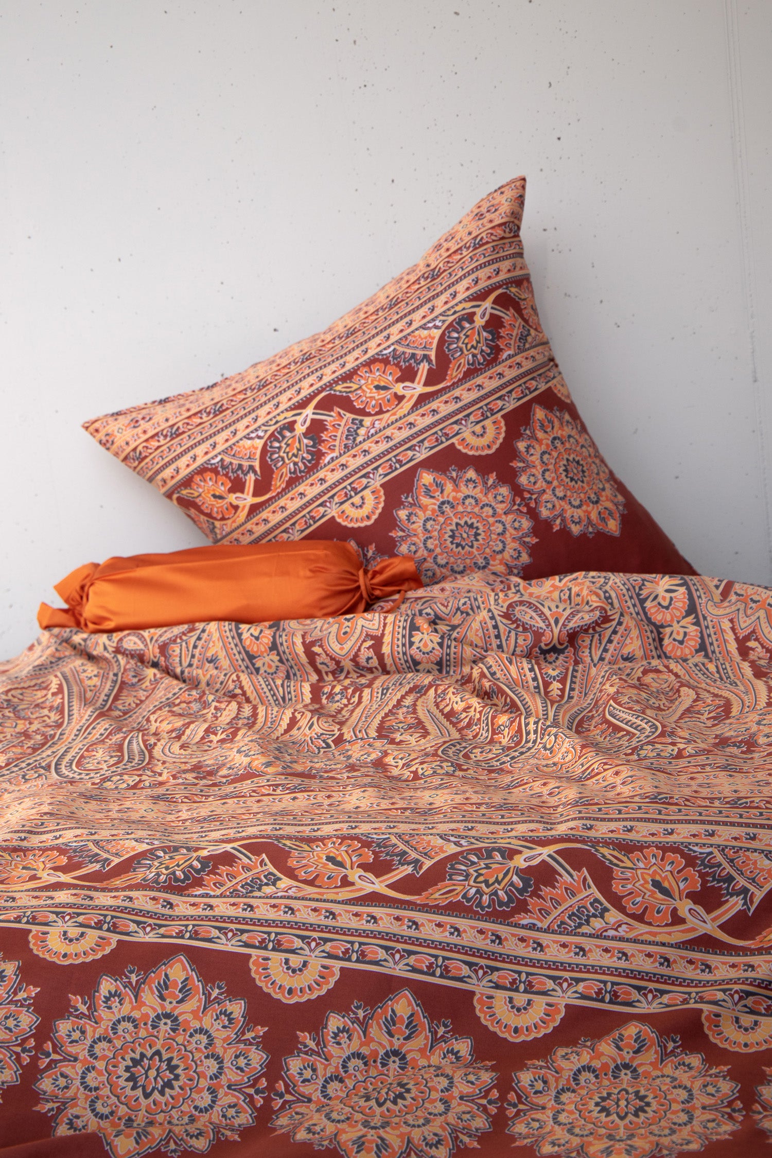 Mehrere Kopfkissen und eine Bettdecke bezogen mit seidig-weicher Satin Bettwaesche von Casatex mit einem Muster in der Farbe Braun. Modell Kirana Terra/Anthrazit.