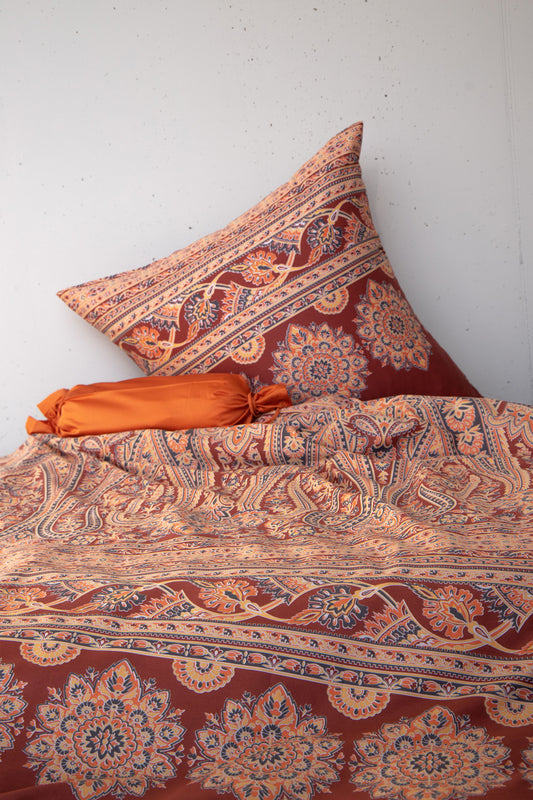 Mehrere Kopfkissen und eine Bettdecke bezogen mit seidig-weicher Satin Bettwaesche von Casatex mit einem Muster in der Farbe Braun. Modell Kirana Terra/Anthrazit.