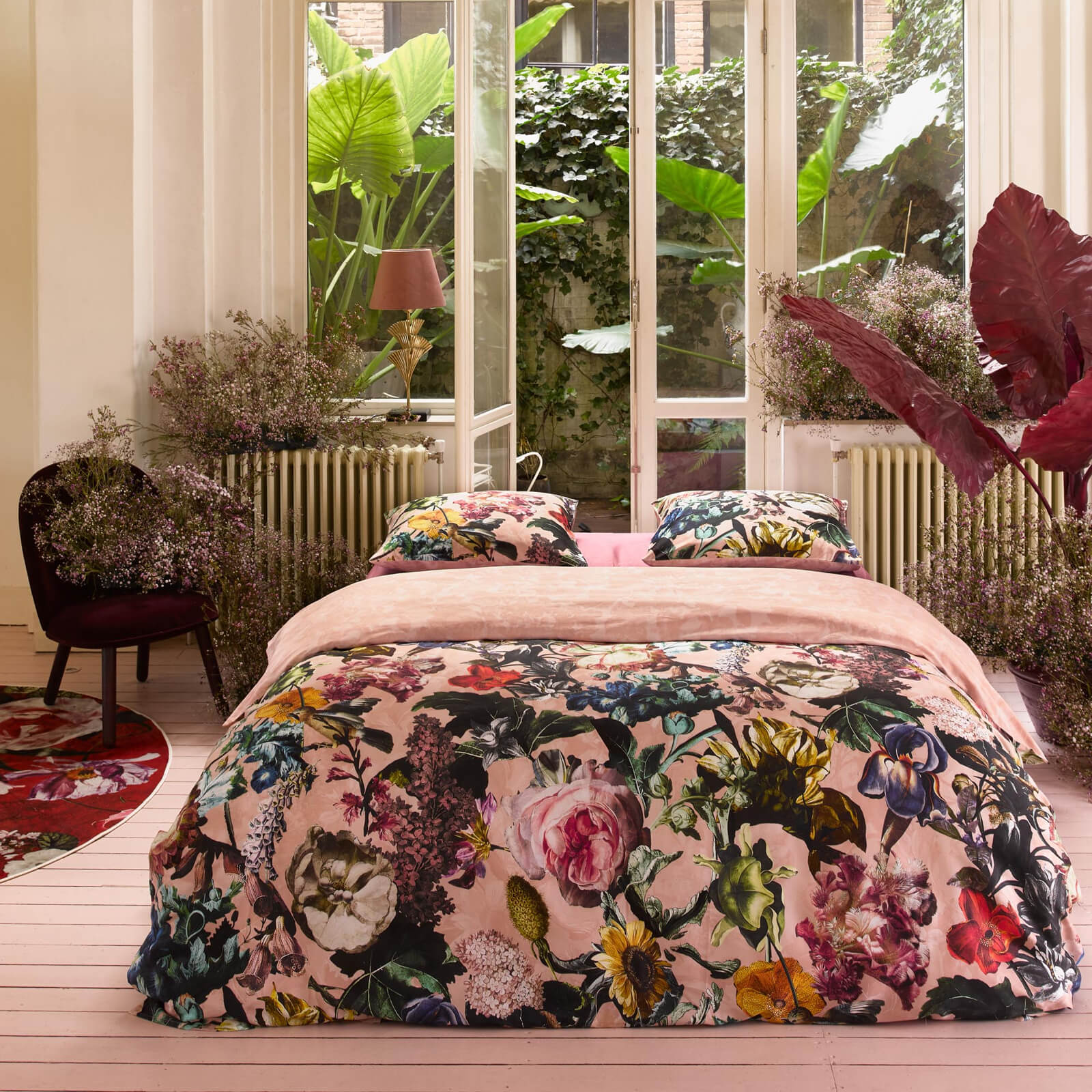 Ein Bettbezug-Set aus mehreren Kopfkissen und einer Bettdecke bezogen mit Satin Bettwaesche aus 100 Prozent Baumwolle mit Muster aus Blumen in der Farbe Rosé. Modell Famke Rose.
