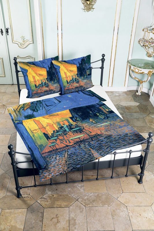 Auf einem Bett liegen mehrere Kopfkissen und eine Bettdecke bezogen mit Satin Bettwaesche aus 100 Prozent Baumwolle mit Muster des Bildes Das Nachtcafé von Vincent van Gogh in der Farbe Blau. Modell Das Nachtcafé.