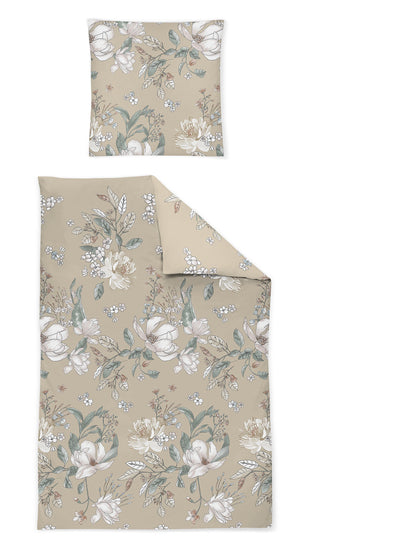 Ein Kopfkissen und eine Bettdecke bezogen mit Satin Bettwaesche mit einem Muster aus Blumen in der Farbe Beige. Modell Fleur.