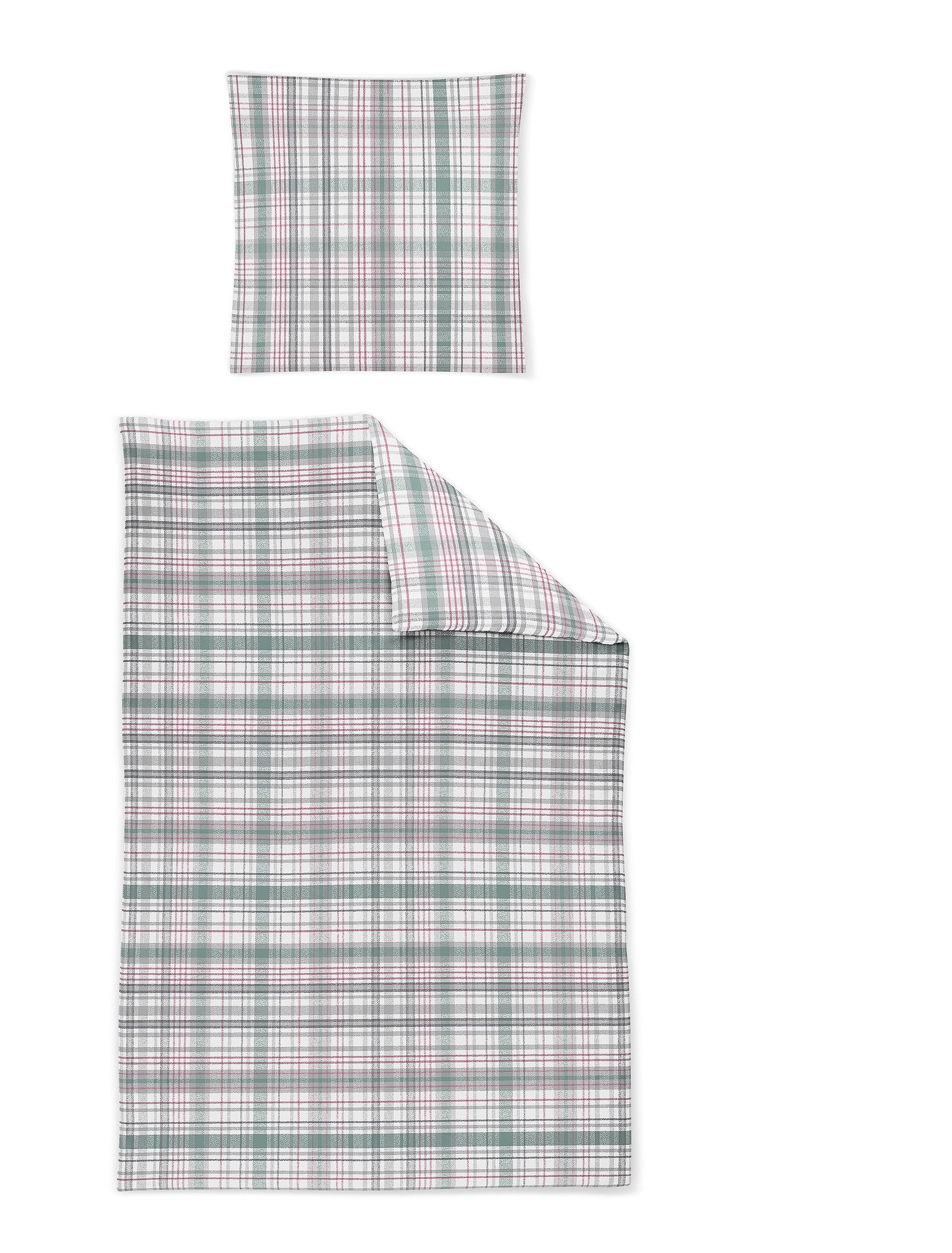 Ein Kopfkissen und eine Bettdecke bezogen mit Satin Bettwaesche mit einem Muster aus Quadraten in der Farbe Rosa. Modell Karo Rosa Gruen.