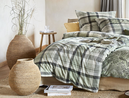 Auf einem Bett liegen mehrere Kopfkissen und eine Bettdecke bezogen mit Soft Seersucker Bettwaesche aus 100 Prozent Baumwolle mit Muster aus Quadraten in der Farbe Gruen. Modell Easy Caro.