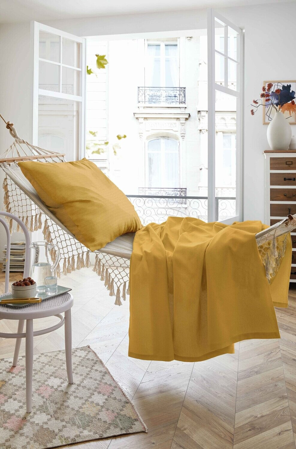 Auf einer Haengematte liegt ein Kopfkissen und ein Sommertuch in der Farbe Gelb. Modell Sommer-Set Mustard.