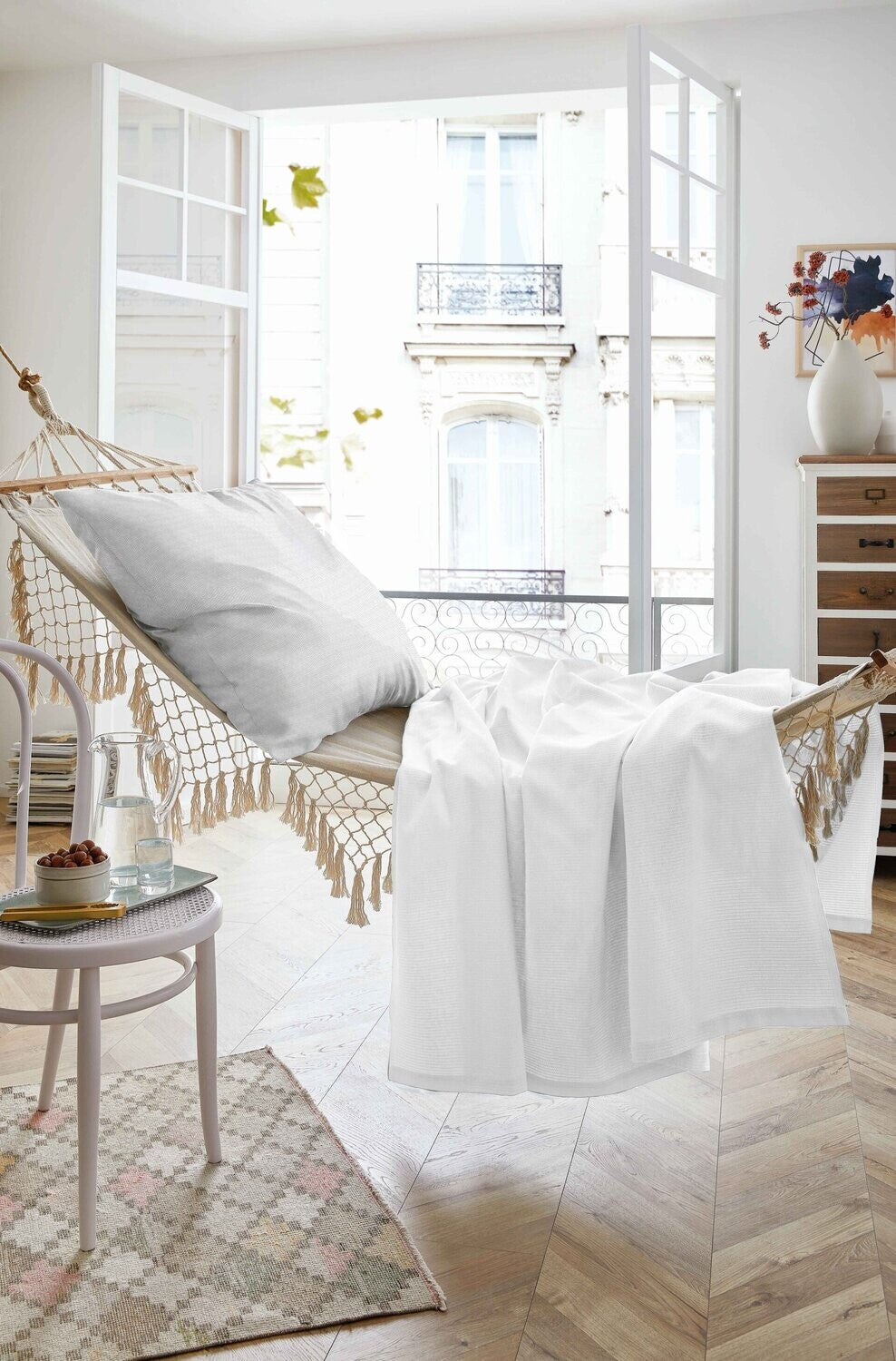 Auf einer Haengematte liegt ein Kopfkissen und ein Sommertuch in der Farbe Weiss. Modell Sommer-Set White.